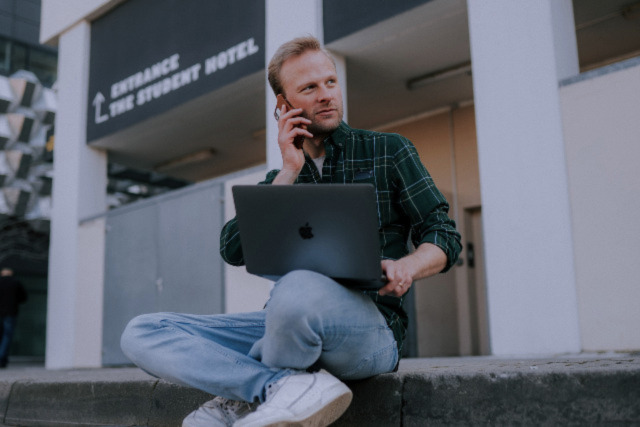 A picture of a business owner talking on the phone while working on their online business with Darren and Mike on their laptop.