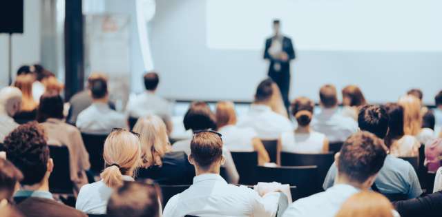 A speaker presenting at a business conference, engaging the audience with insightful information and strategies.