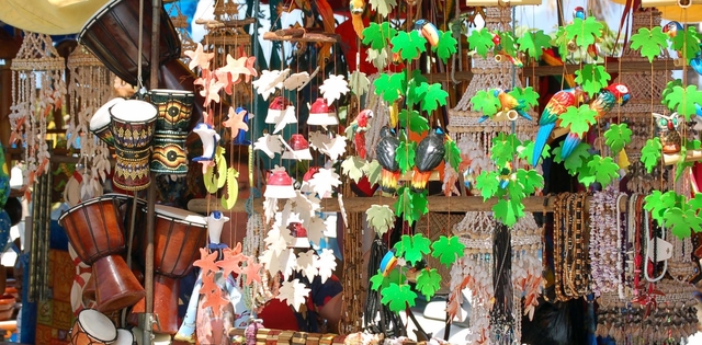 An array of goods ranging from handmade tote bags and jewelry to wind chimes and drums in a Caribbean market stall.
